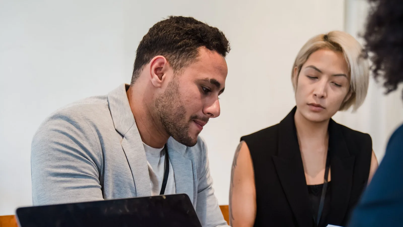 Two office collaborators reviewing work beside an unbranded laptop